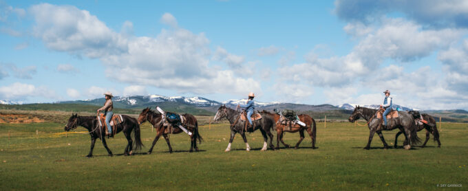 Amy David, Emilé Zynobia and Tatum Monod start their journey into the Wyoming Range saddled up with their skis loaded onto pack mules. The trip started at the David Ranch in Merna, WY, and ended on the other side of the snowy peaks in the distance. Photo: Sky Garnick